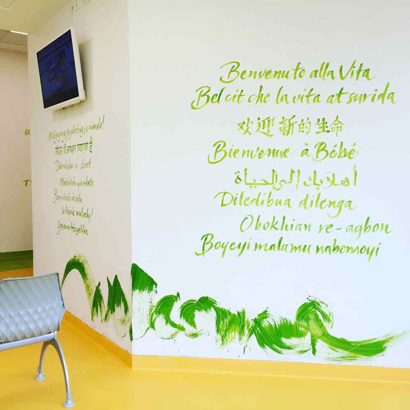 parete bianca con scritte verdi e intervento pittorico